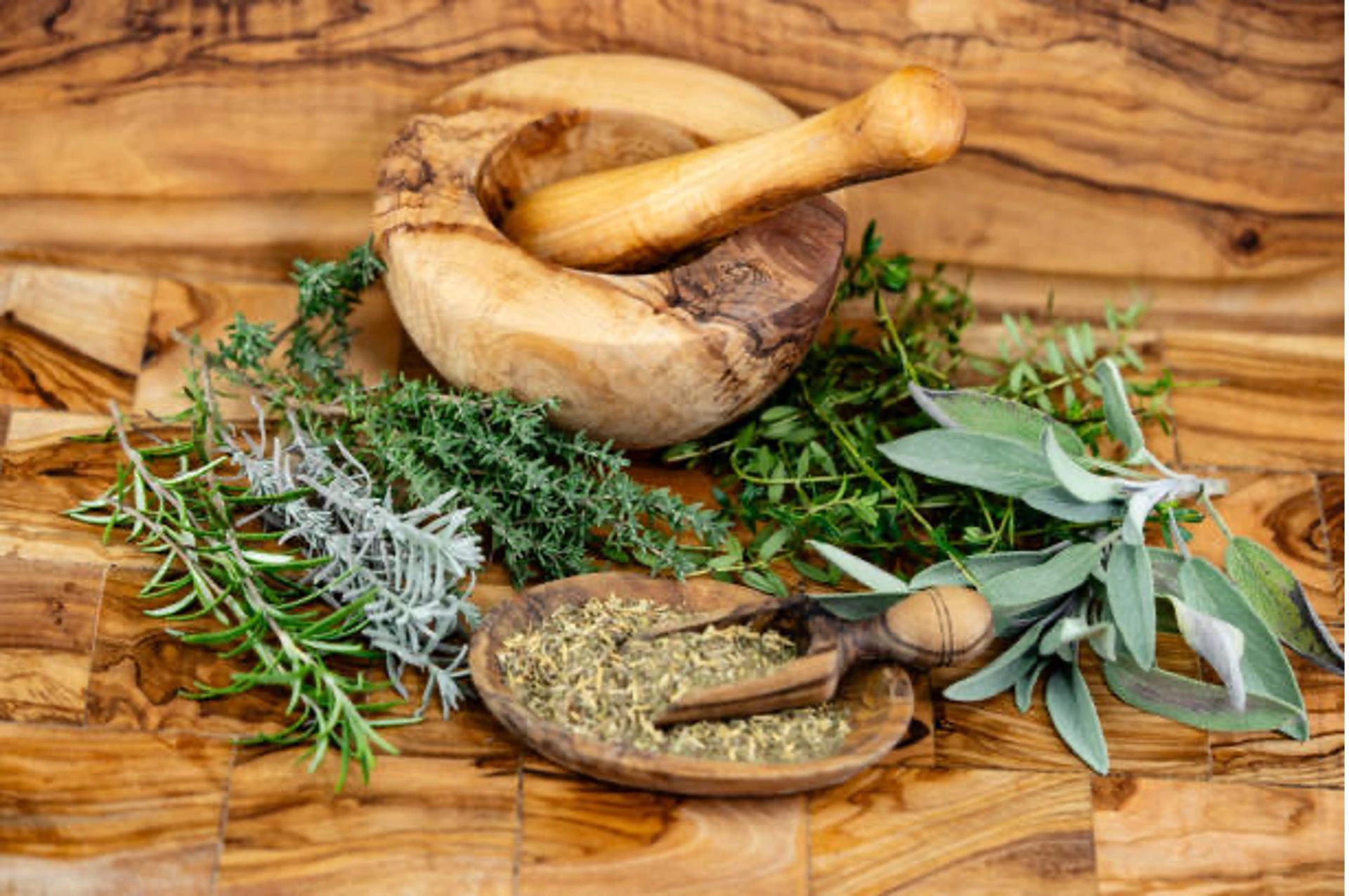 Ayur Picture 3 - Dr. Gayatri Damodaran | Ayurveda Doctor In Mira Bhayander, Mumbai Wooden mortar and pestle with fresh herbs (rosemary, thyme, sage) on a rustic wooden surface for cooking.